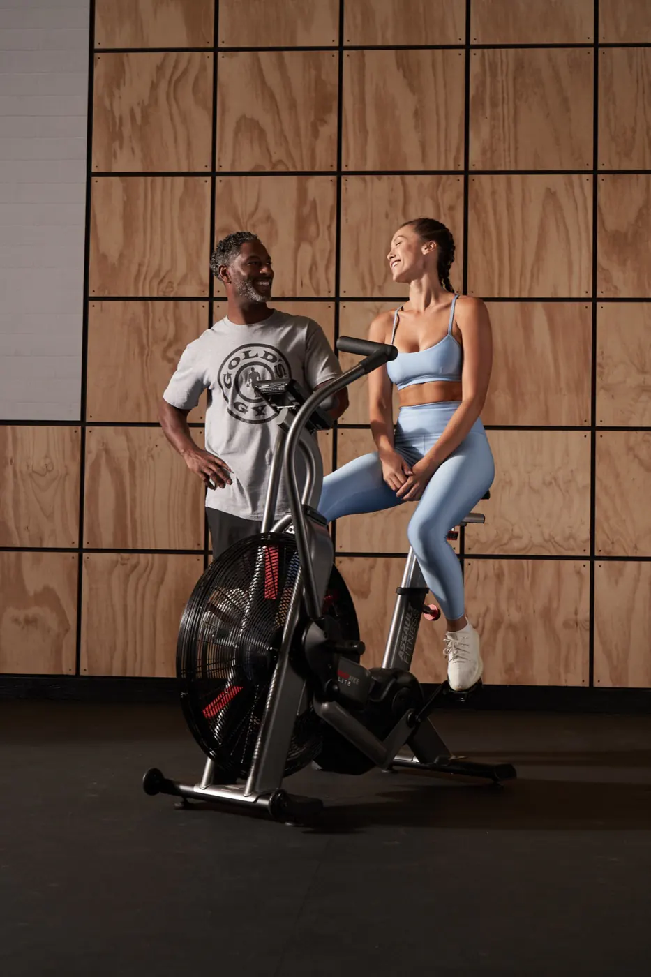 A trainer coaching a member on an air bike